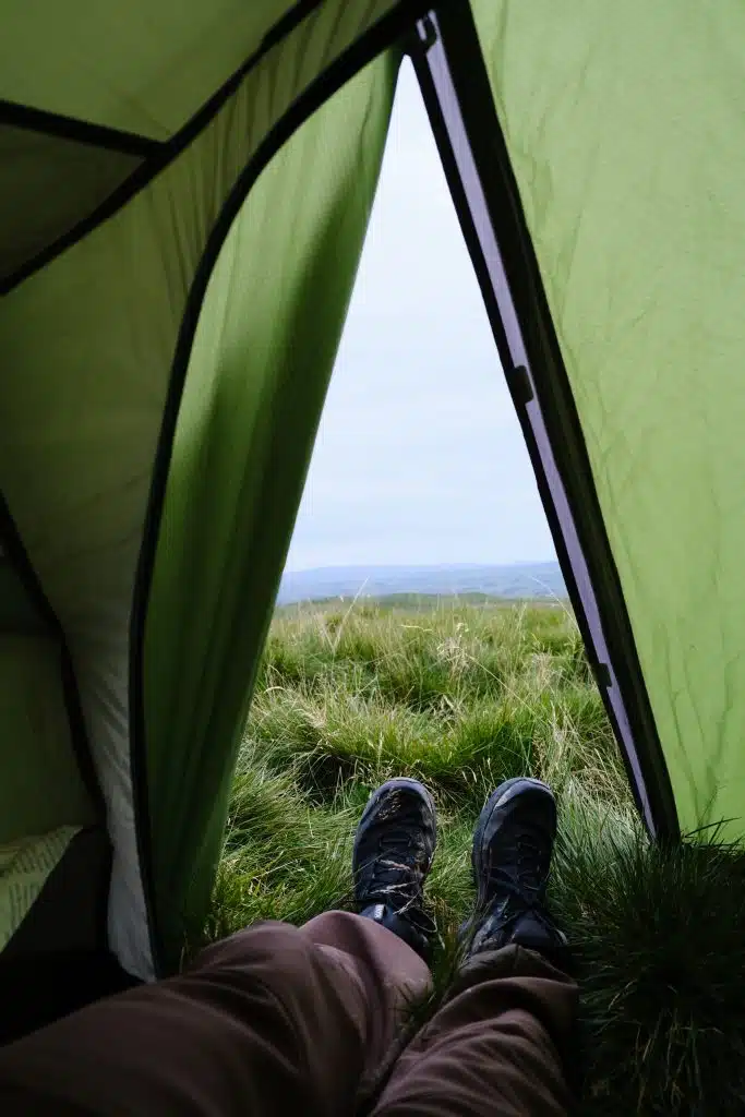Legs coming out of tent with mountain view