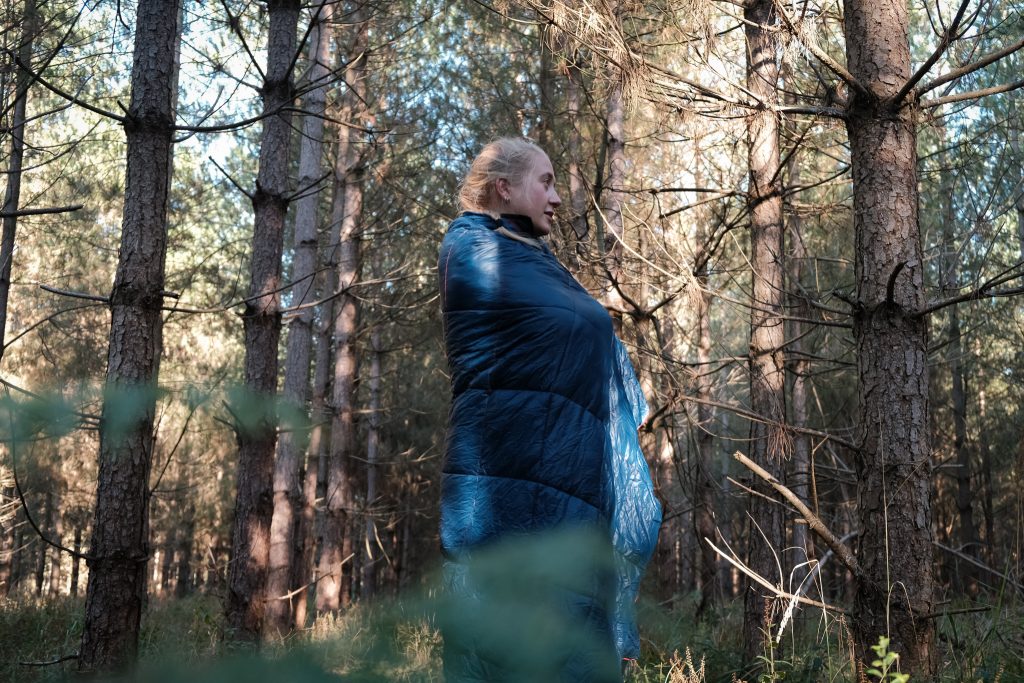 Girl in woods wearing a Rumpl blanket vegan alternative to wool