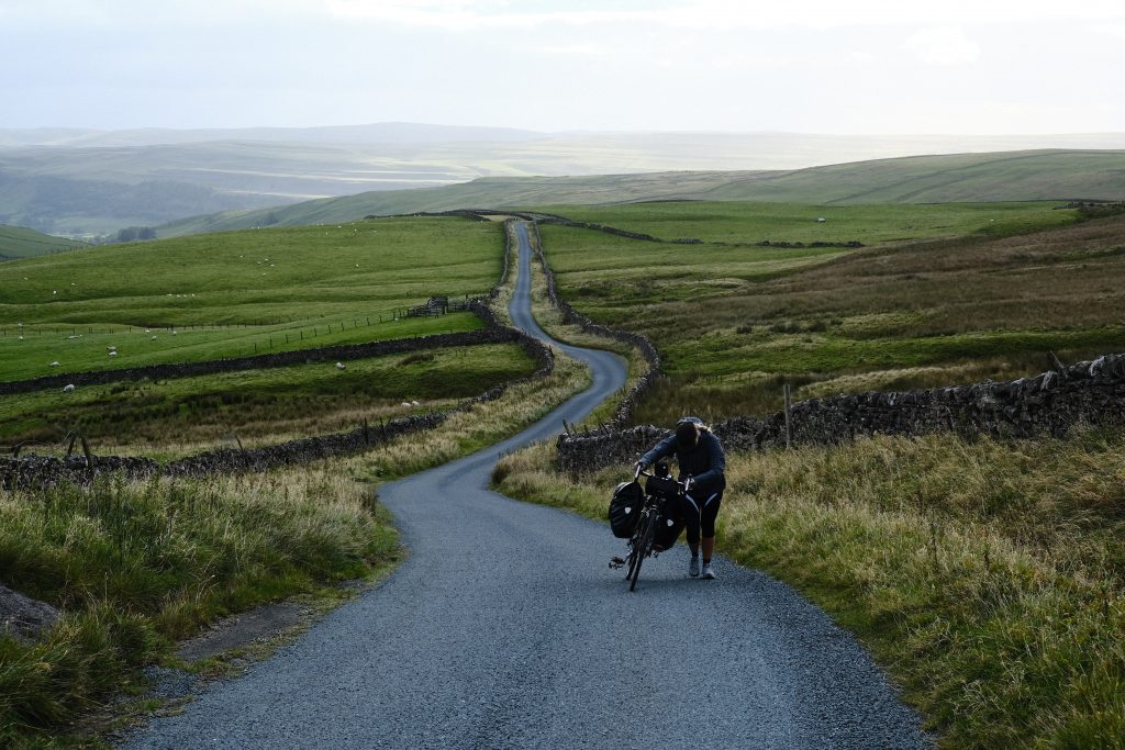 Woman pushing bike up steep hill