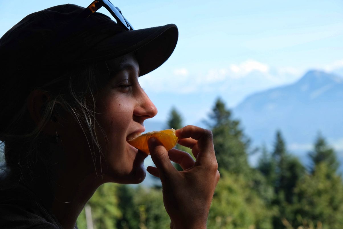 Girl eating an orange in the mountains
