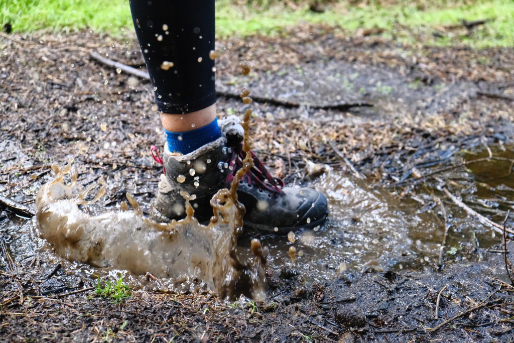 Girl wearing waterproof hiking boots and stepping into puddle