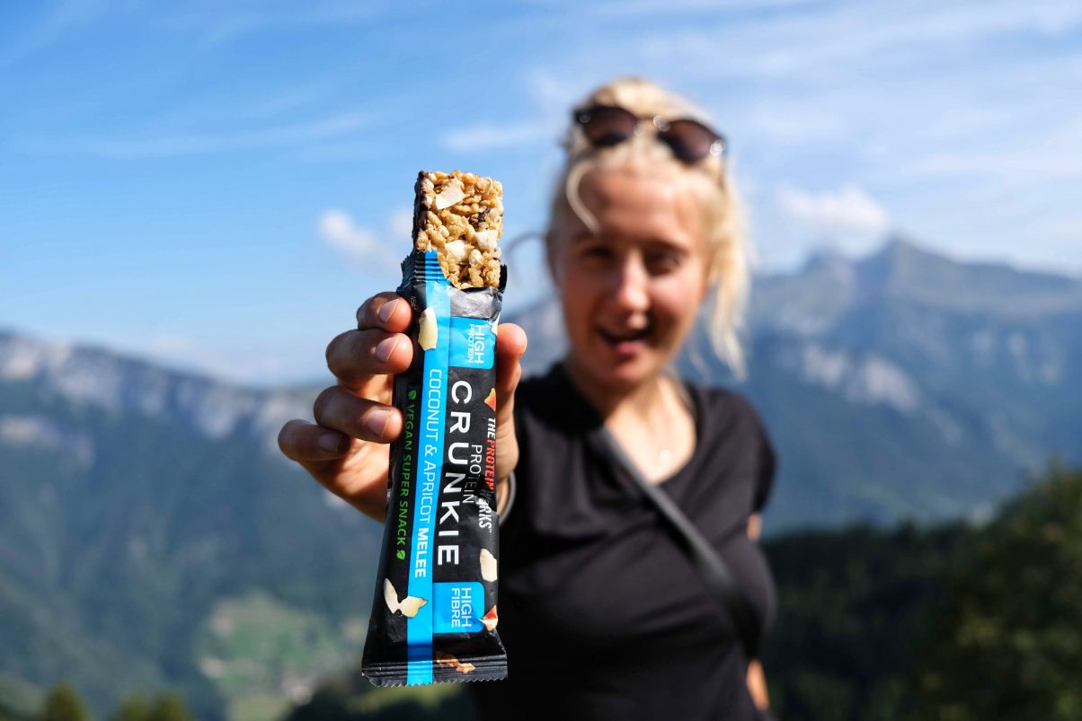 Girl in mountains holding vegan protein bar