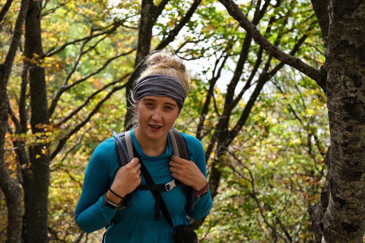Girl hiking through forest wearing a buff