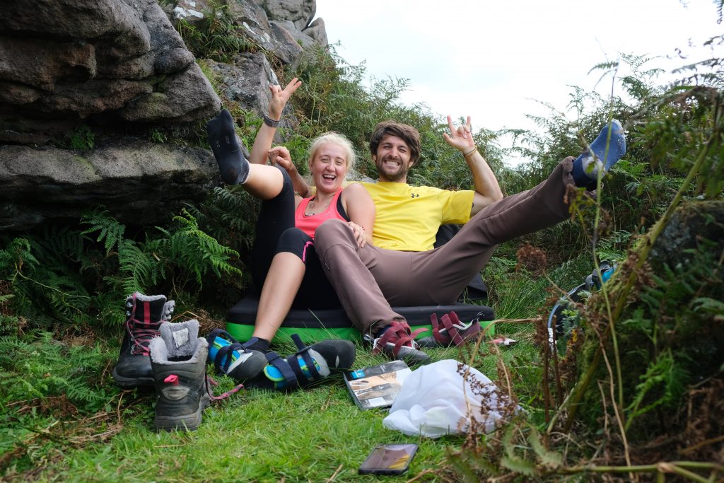 Couple sitting of climbing crash pad in countryside