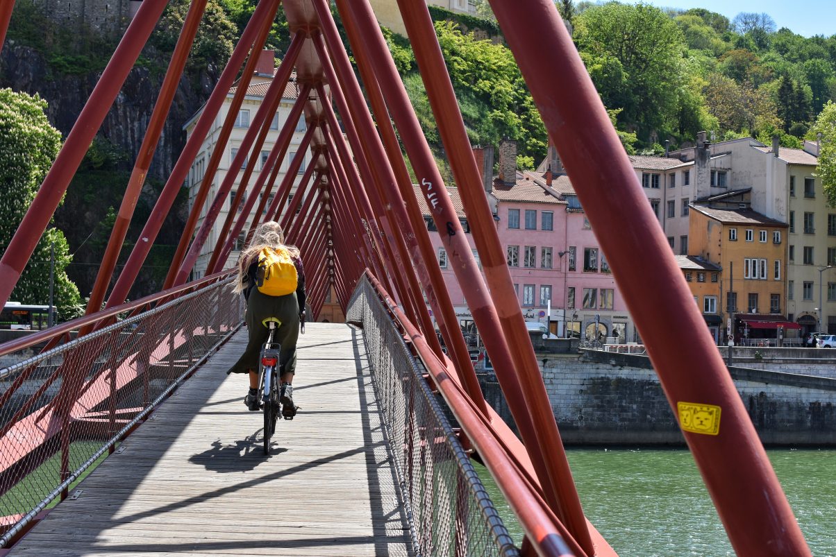 Girl on bike crossing bridge structure