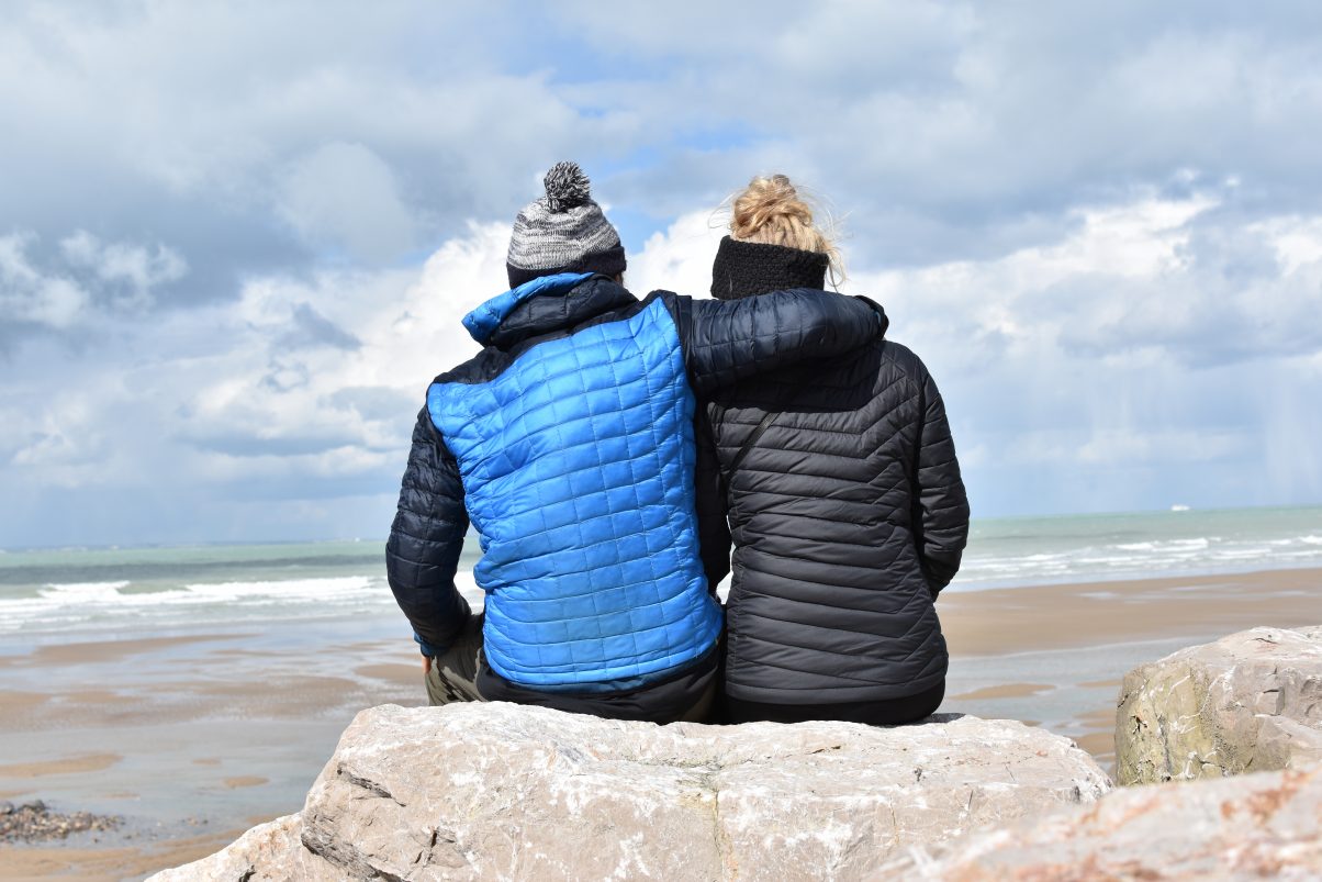 Couple sitting on the coast in insulated jackets