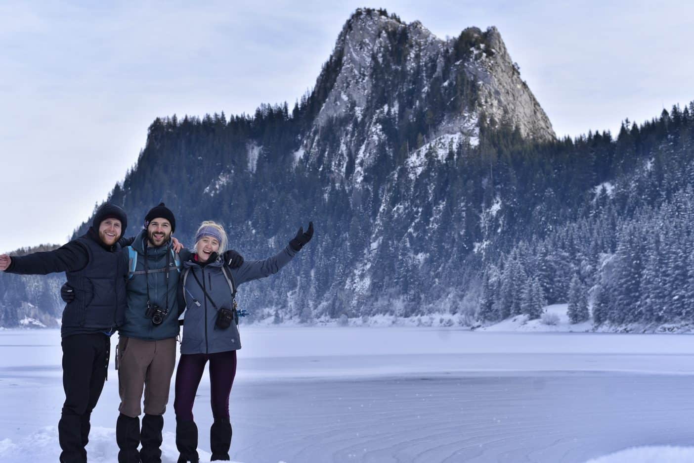 Three people in front of winter mountains 