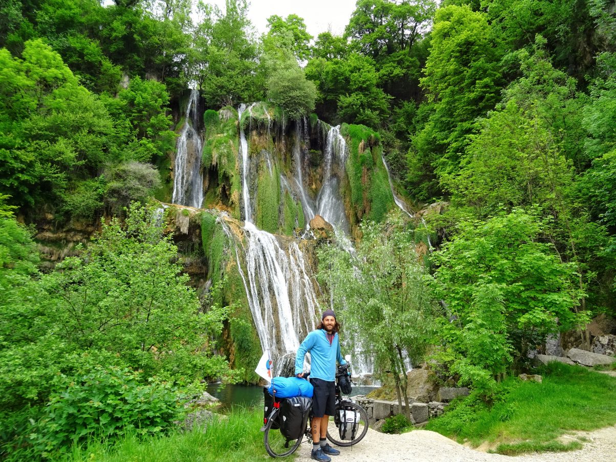 Male cycle tourer in front of waterfall