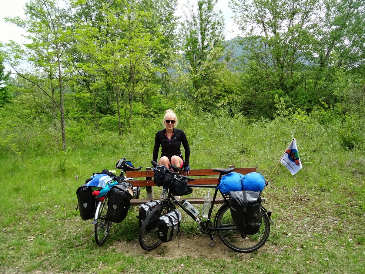Female cycle touring sitting with bike