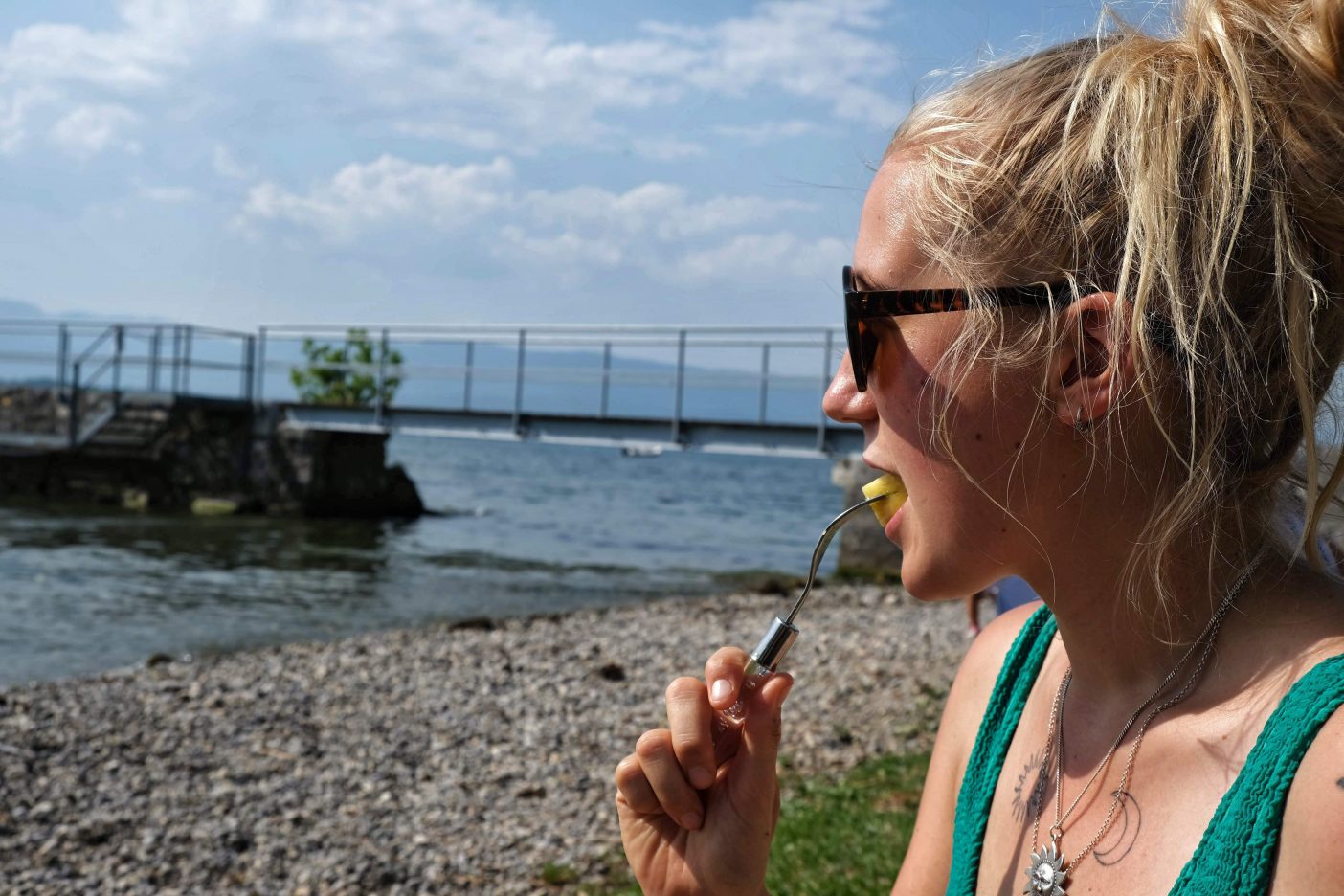 Girl eating pineapple by lake 