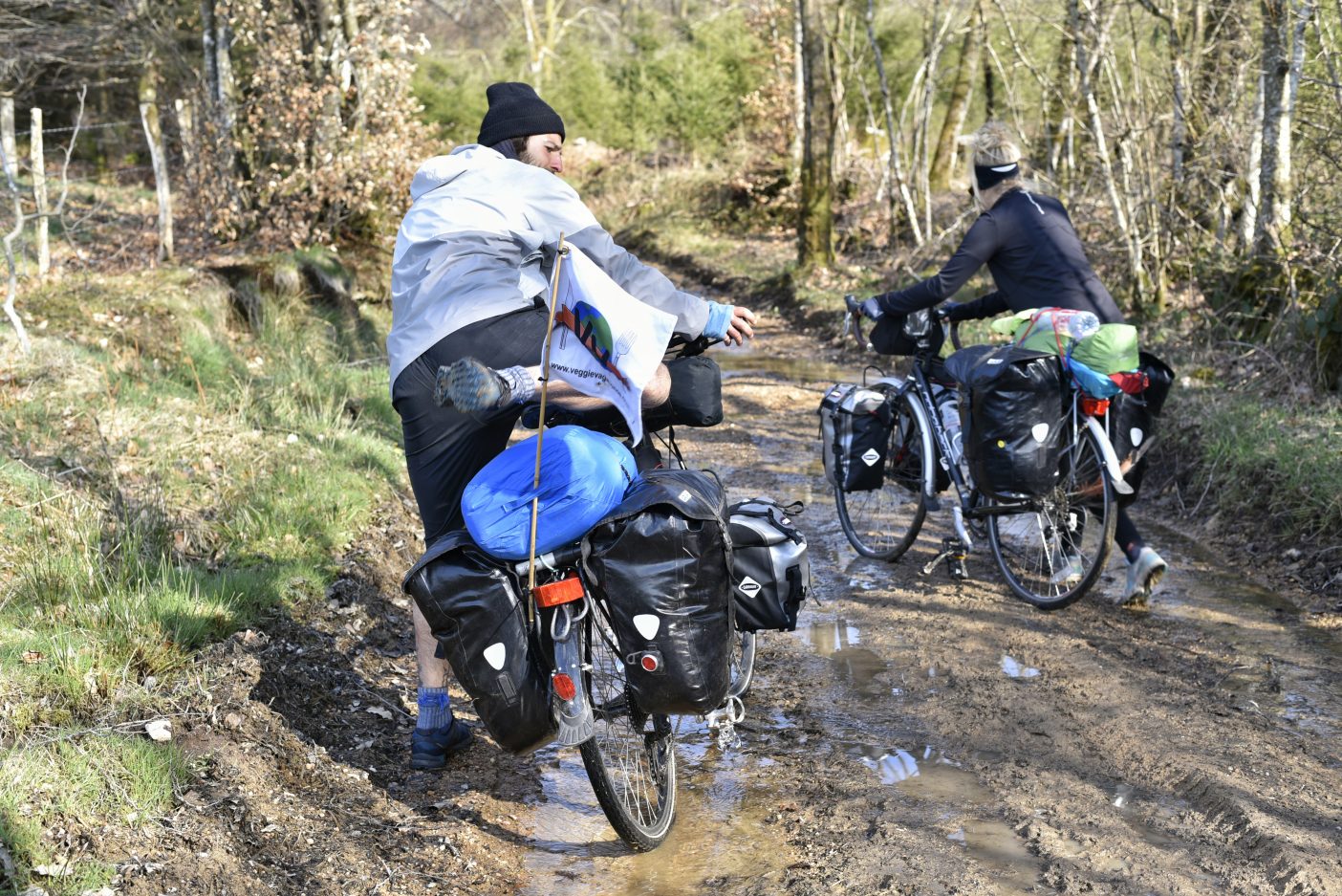 Cyclist pushing bikes through mud