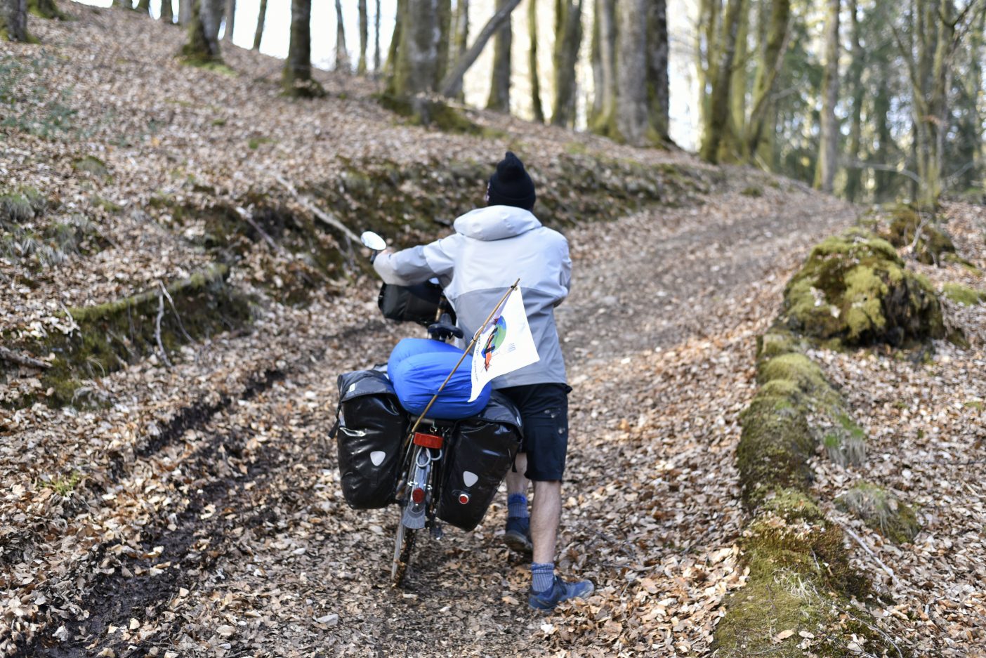 Traveller pushing bike up off-road track 